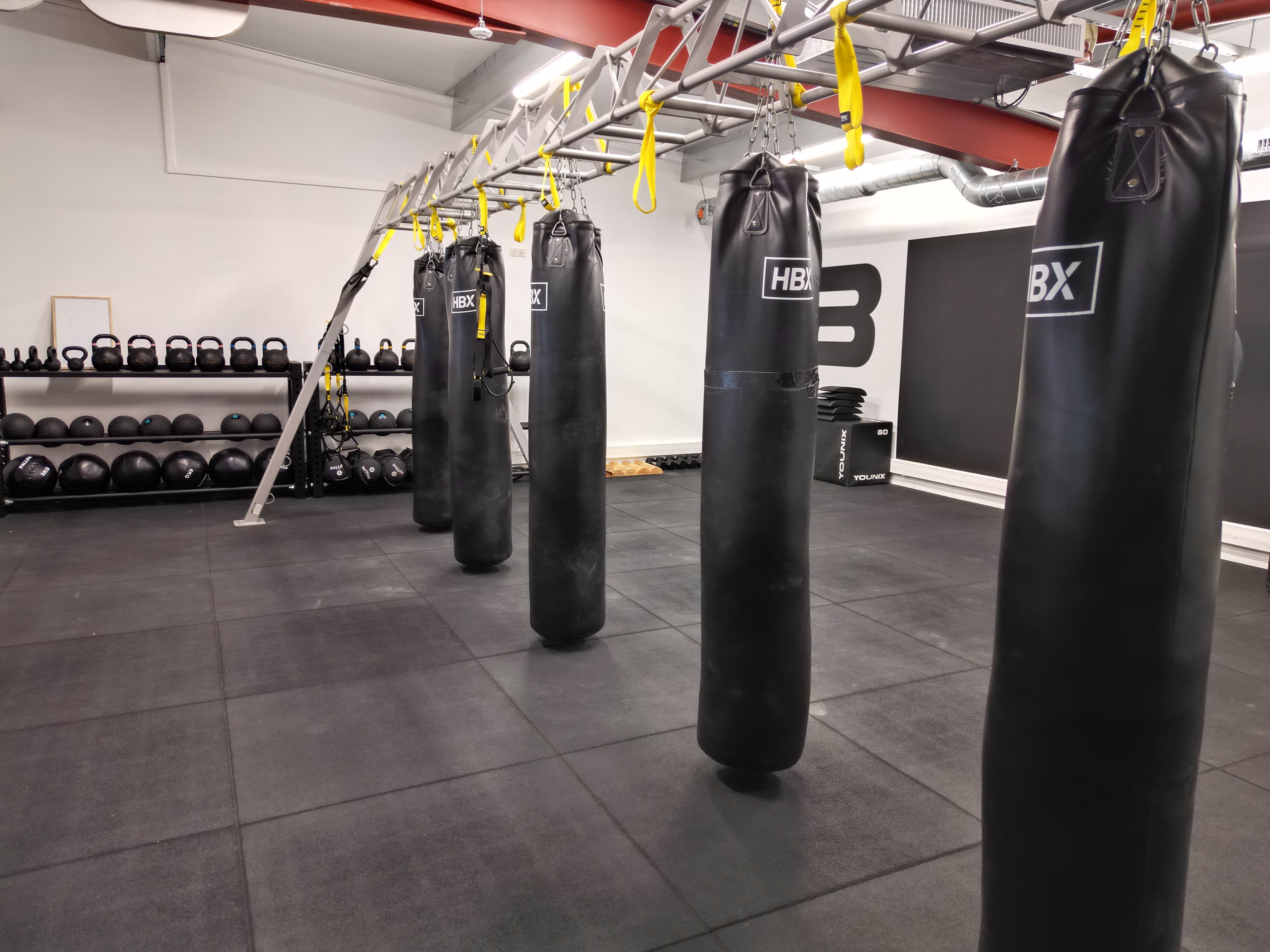 Salle avec sacs de frappes et altères