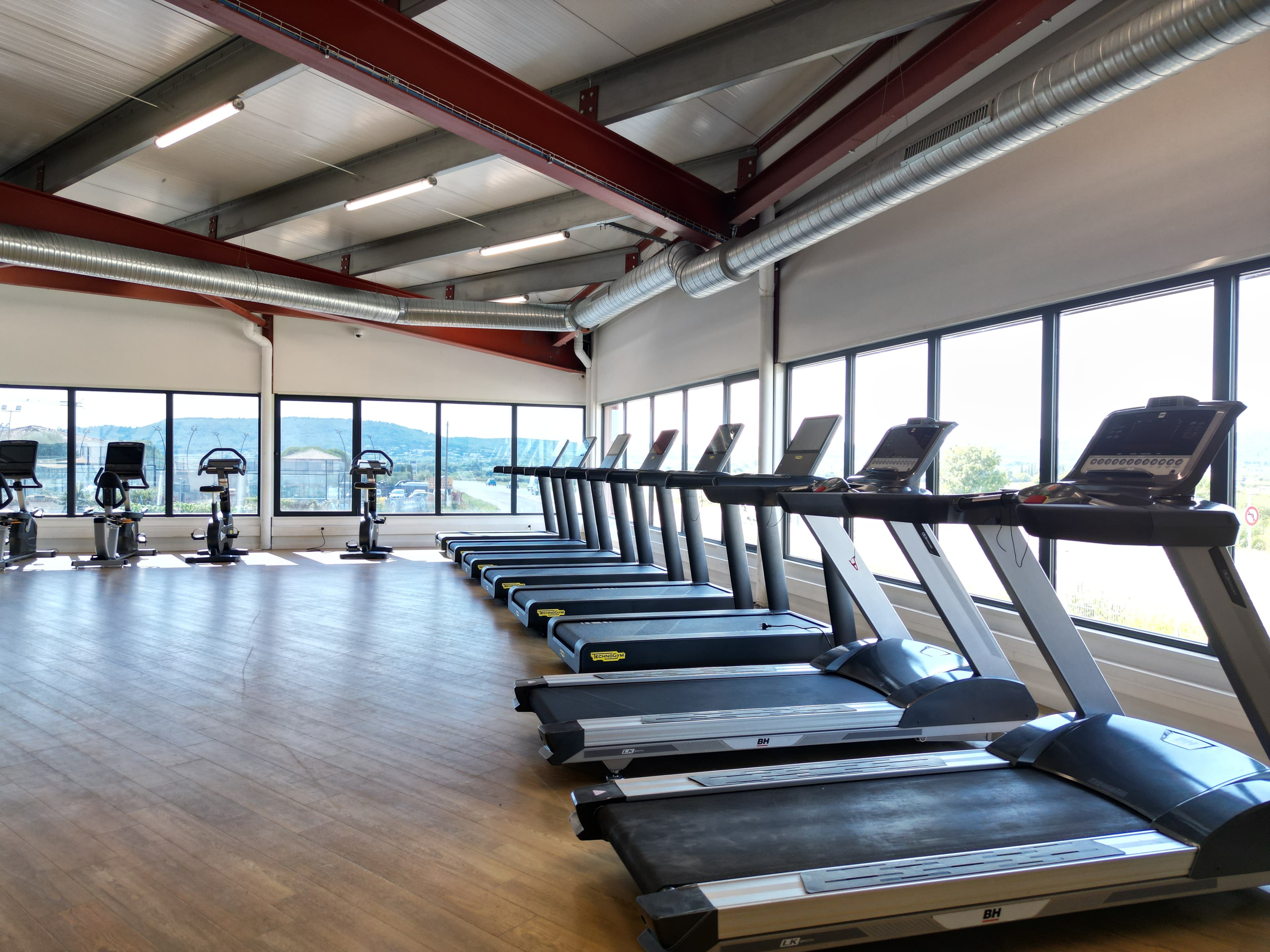 Salle cardio avec de nombreux tapis de course et une atmosphère lumineuse